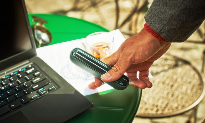 IQOS ILUMA w dłoni kierującej się w stronę laptopa