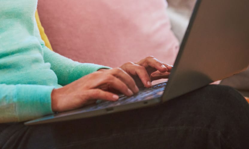 Osoba trzymająca laptopa na kolanach