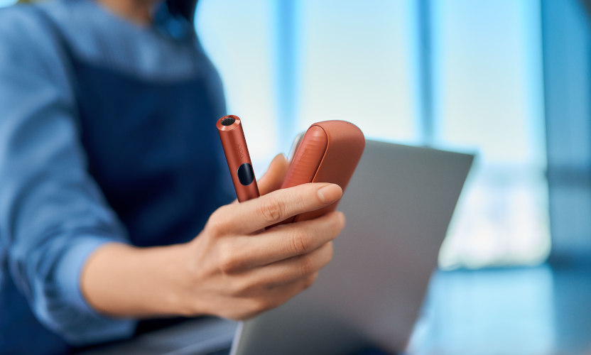 Podgrzewacz IQOS ILUMA i z przenośną ładowarką trzymane w dłoni