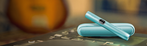 Podgrzewacz IQOS ILUMA i z przenośną ładowarką, niebieskie, leżące na klawiaturze
