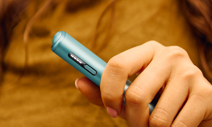 Podgrzewacz tytoniu IQOS ILUMA i ONE w kolorze Breeze Blue, trzymany w dłoni