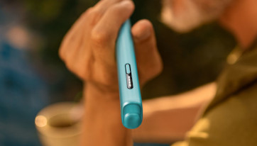 Podgrzewacz tytoniu IQOS ILUMA i ONE w kolorze Breeze Blue trzymany w dłoni