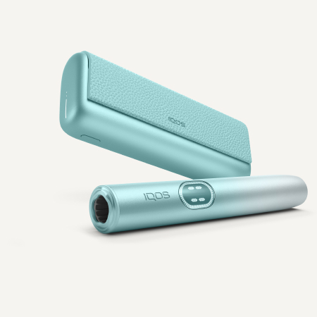 Podgrzewacz tytoniu IQOS ILUMA i PRIME Breeze Blue z widocznym ekranem dotykowym, lezący obok przenośnej ładowarki w tym samym kolorze
