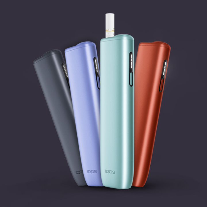 Podgrzewacze tytoniu IQOS ILUMA i ONE w czterech kolorach , w jednym z urządzeń wsunięty wkład tytoniowy DELIA