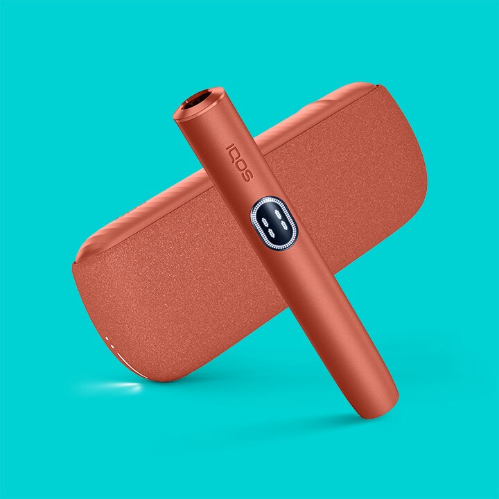 Podgrzewacz i przenośna ładowarka IQOS ILUMA i, czerwone, na turkusowym tle